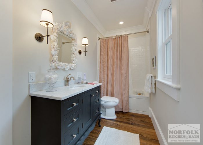 dark black vanity in bath with white stone and mirror with shells
